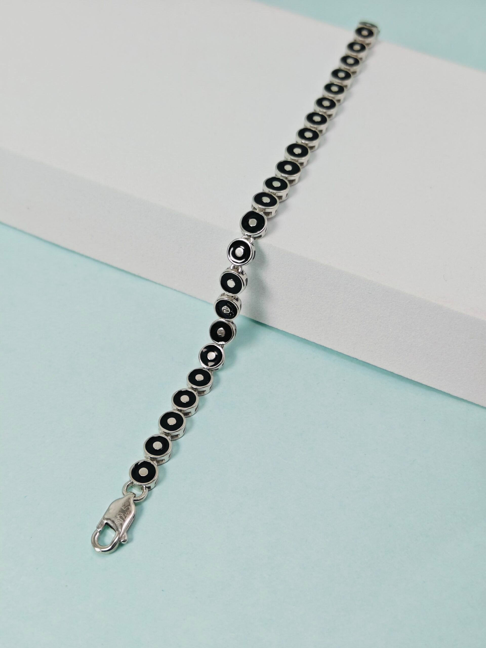 Silver bracelet with black beads on a light blue background